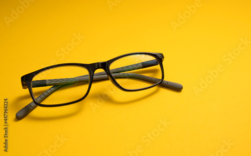 Children's glasses lie on a yellow close-up with space for text. Copy Space. The concept of children's myopia, astigmatism, vision problems, visual impairment.