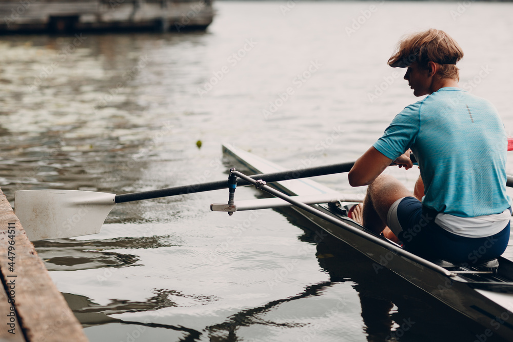 Sportsman single scull man rower prepare to competition with boat on pier