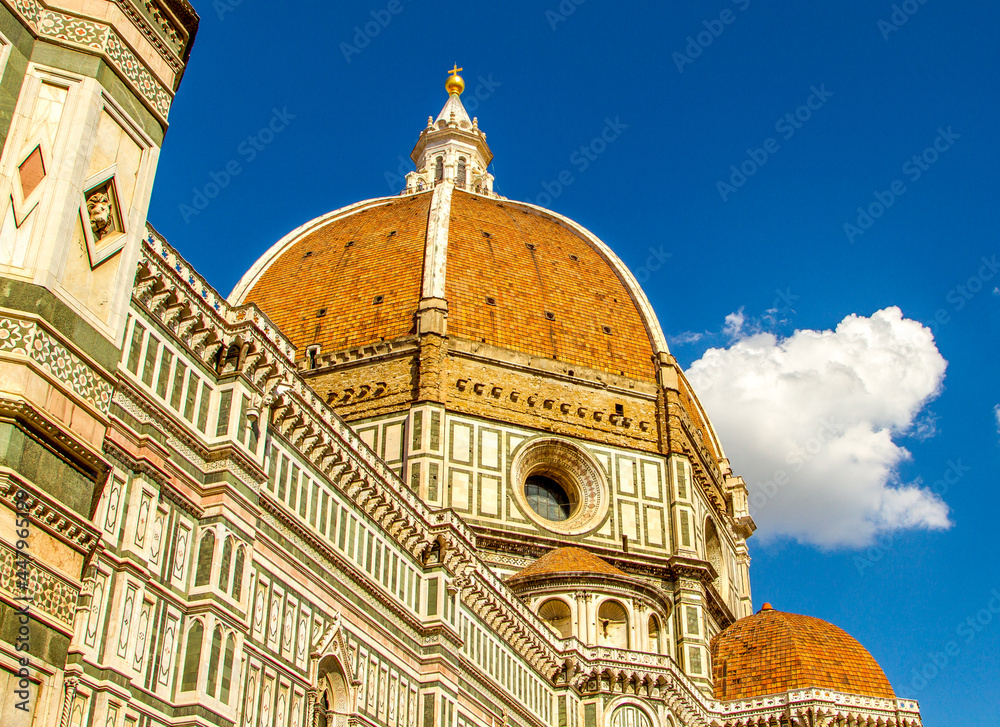 The beautiful and ornate Dome of Florence Cathedral in Italy against a blue sky with a fluffy white cloud