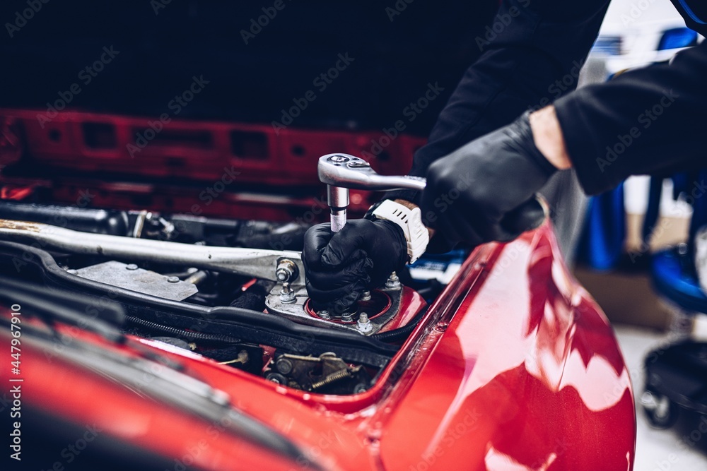 Repairman in car service repairing engine or other car part