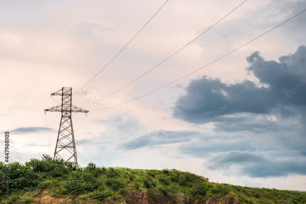 Landscapes of Siberia. The tower of the high-voltage line on a hill against the background of sunset sky.