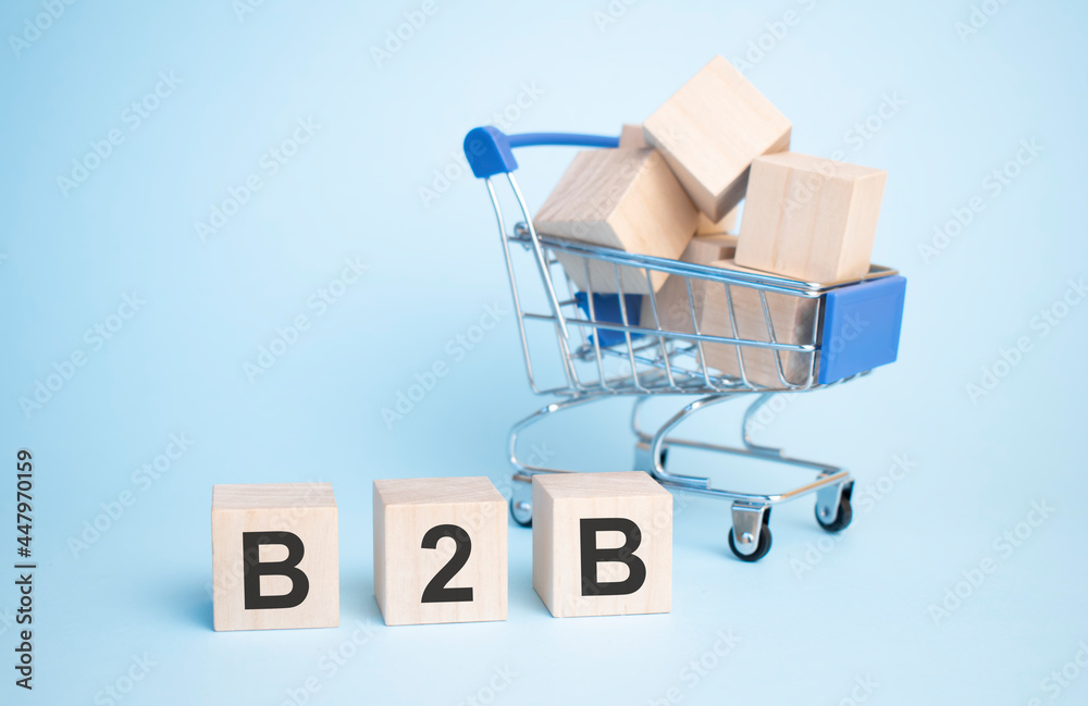 Text b2b on wooden cube with shopping cart isolated over background.