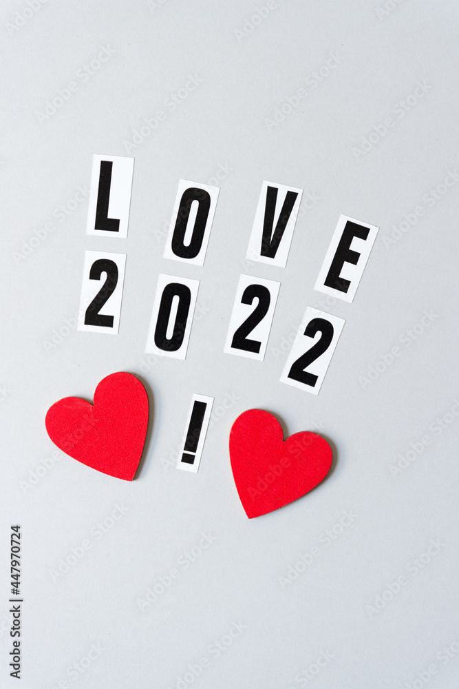 Obraz premium love 2022 with an exclamation mark and two hand painted red hearts on a light gray paper background with copy-space