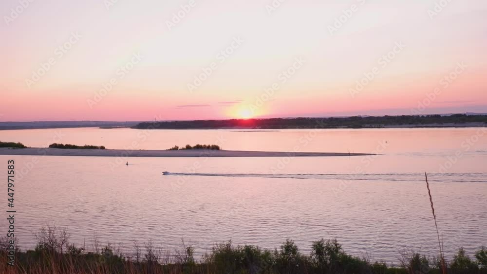 The boat is sailing along the river at sunset. Beautiful landscape by the river. The boat is sailing along the river at sunset. Beautiful landscape by the river.