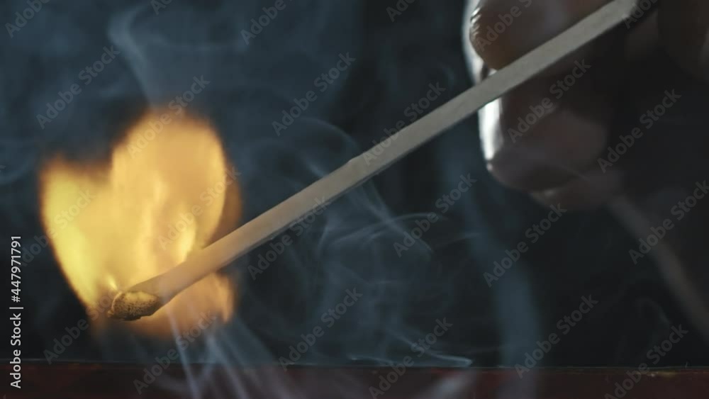 Extreme close up shot of unrecognizable person lighting match against dark background Extreme close up shot of unrecognizable person lighting match against dark background