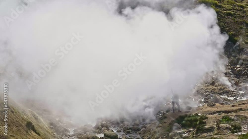 Hiking and eco tourism woman waves hand standing near geyser