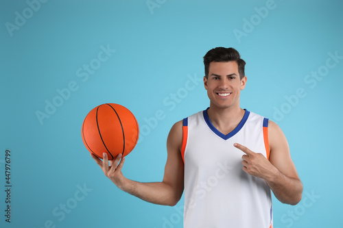 Basketball player with ball on light blue background