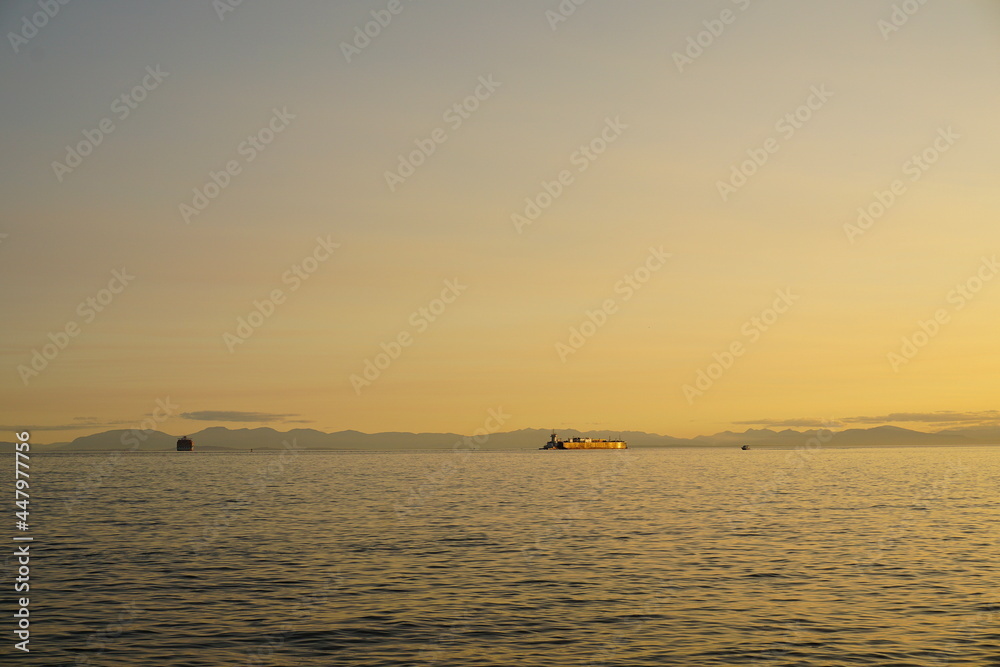 Incredible beautiful colorful sunset over the Pacific ocean. Barges on background.