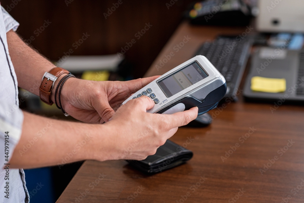 Manos de una persona utilizando una maquina para tarjetas de crédito para cobrar dinero Manos de una persona utilizando una maquina para tarjetas de crédito para cobrar dinero