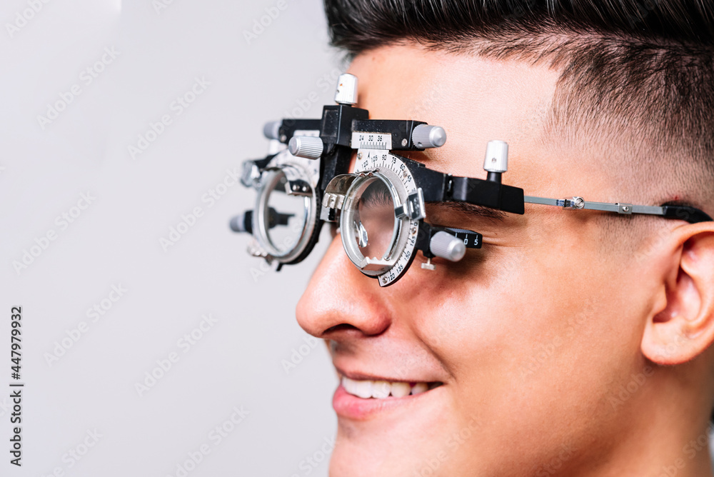 Primer plano de un Joven hombre con unas gafas de medición para realizar exámenes de la vista por el oftalmólogo  - obrazy, fototapety, plakaty 
