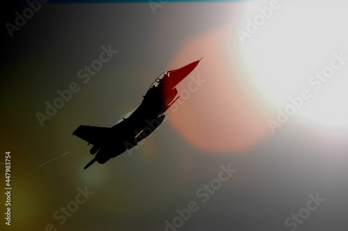 Air fighter climbing to sky against background of sun photo