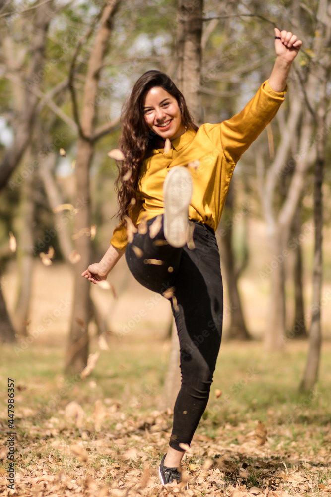 smiling girl kicks dry leaves in a forest smiling girl kicks dry leaves in a forest