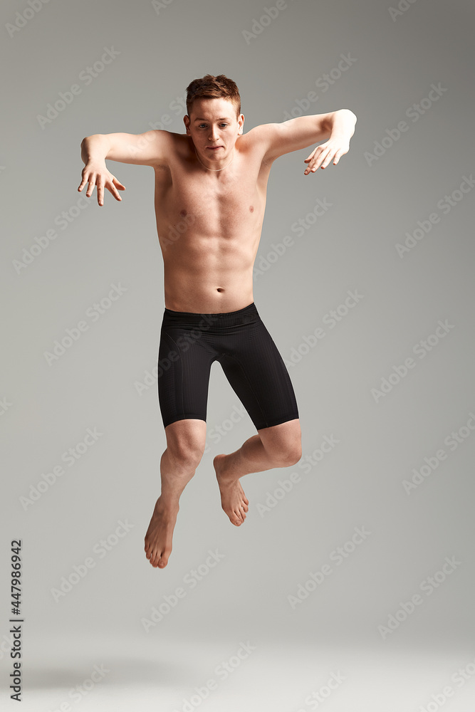 Swimmer in a jump on a gray background, swimming concept, spear space, athlete in swimming trunks for swimming.