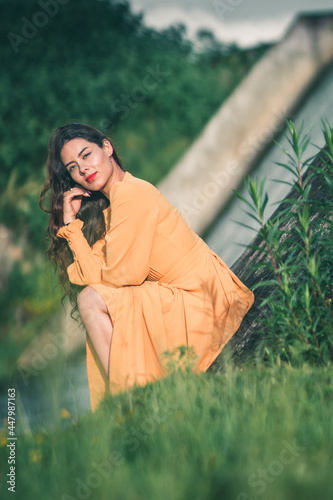 girl sitting in a big yellow dress in the middle of nature with a married woman in the background © Tonatiuh