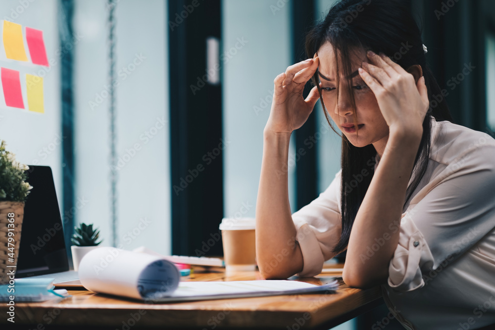 Obraz premium Tired young asian woman feel headache from working problem. Stressed female suffer from headache bad vision sight problem sit at workplace.