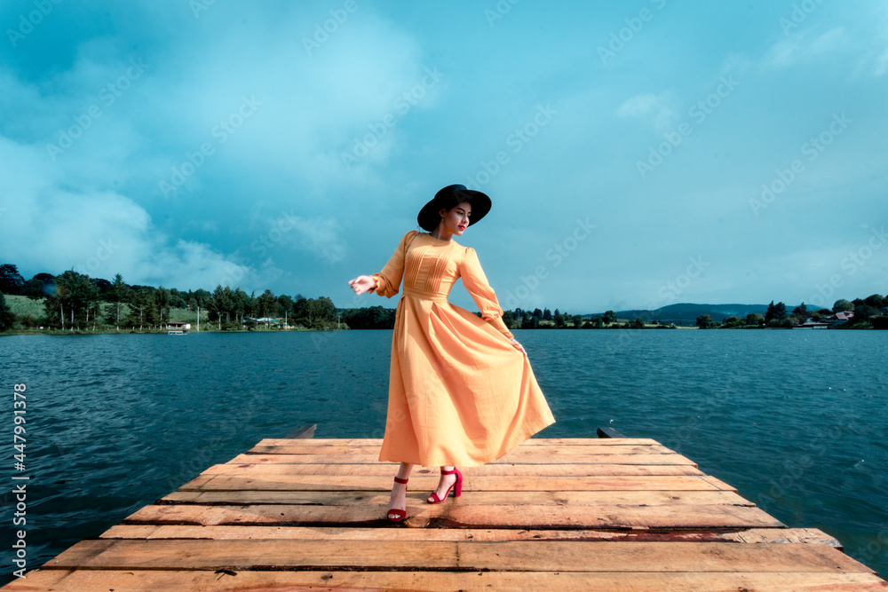 latina girl in a dress on a pier by a lake
