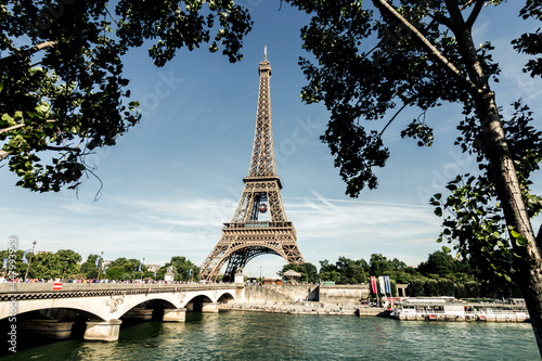eiffel tower seen from the other side of the seine river between trees