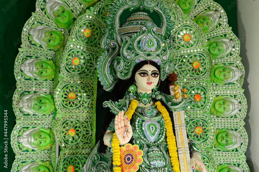 Fototapeta premium Idol of Goddess Saraswati being worshipped inside pandal , a temporary temple, at night. Colorful light on Hindu goddess. Howrah, West Bengal, India.