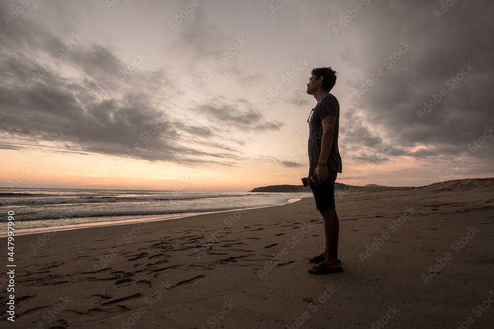 man standing before the immensity of the sea in the sunset