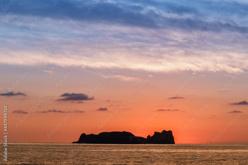 colorful sunset in the pacific sea with an island silhouette in the background