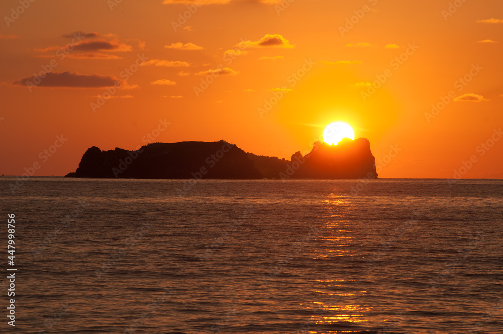 the sun hides behind an island