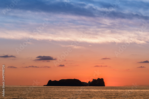 colorful sunset in the pacific sea with an island silhouette in the background © Tonatiuh