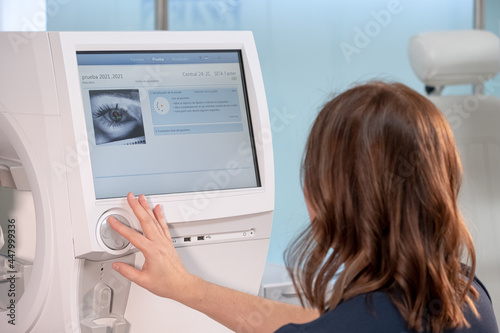 Woman doctor specialist in vision problems sitting in front of ophthalmic diagnostic machine in a clinic or medical hospital