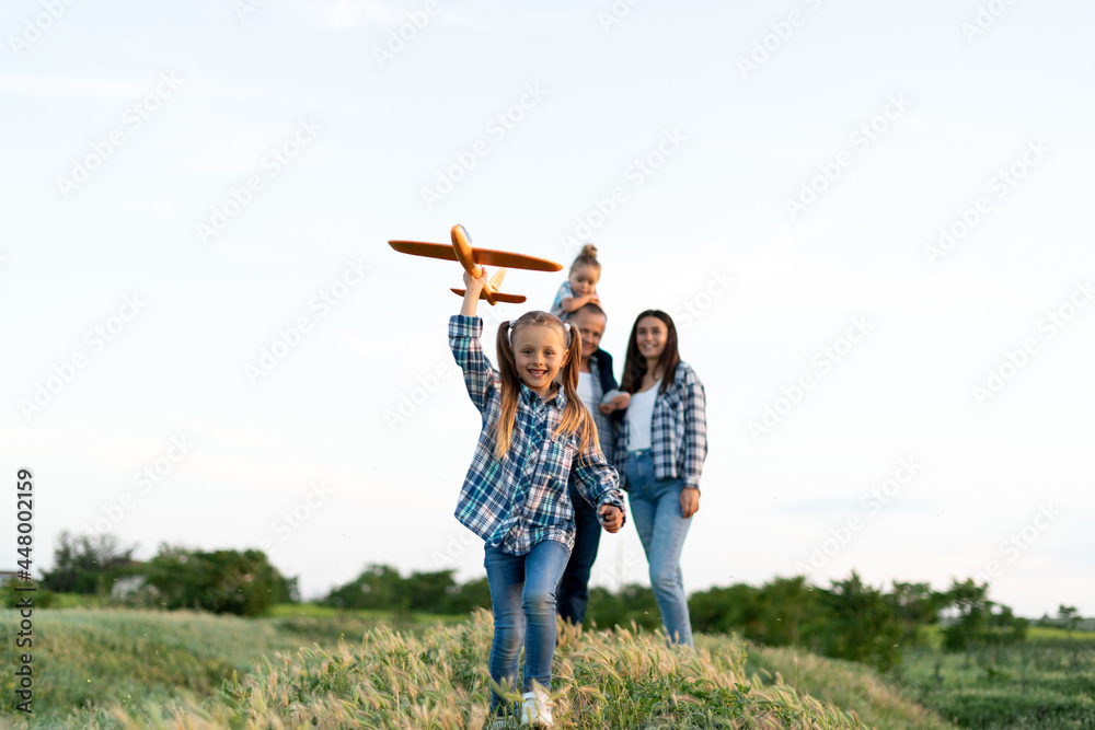 friendly family girl running field launches into the sky a toy plane walks in the evening with her parents and sister. Dad mom and children in the summer on vacation. Family health concept.weekend friendly family girl running field launches into the sky a toy plane walks in the evening with her parents and sister. Dad mom and children in the summer on vacation. Family health concept.weekend