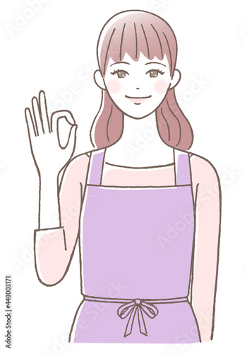エプロンを着てOKサインを出す若い女性