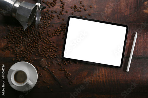 Mock up digital tablet, coffee cup and roasted coffee beans on wooden background.