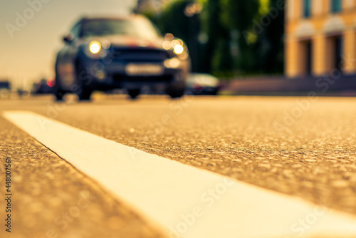 Summer in the city, the car racing down the street. Close up view from the level of the dividing line