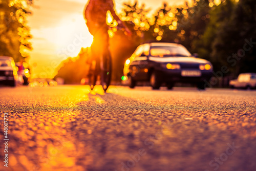 Sunset in the suburbs, the car and a bicycle traveling on the highway. Close up view from the asphalt level