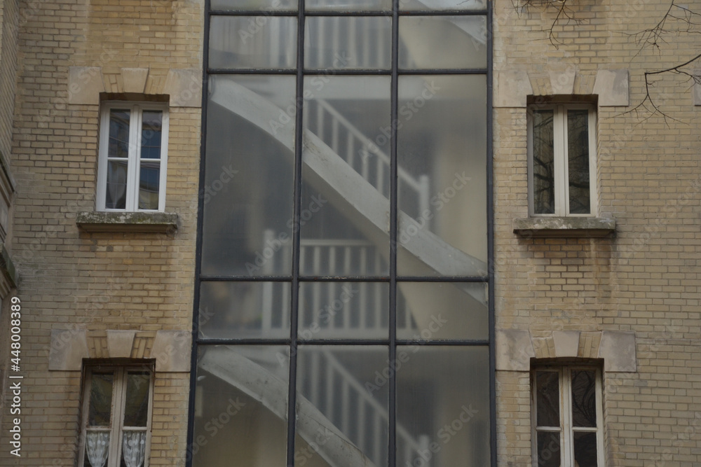 Paris, France - August 19th 2017: Focus on the facade of an old building. There is a large glass roof. The glass is blurry, which gives a particular aspect, like a drawing, to the wooden stairs.
