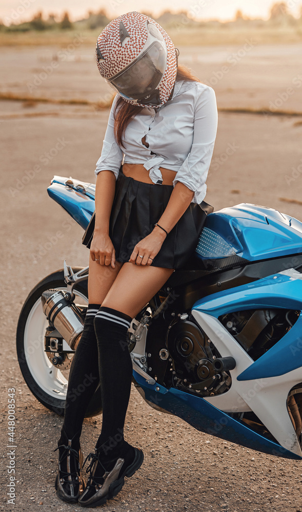 Shy woman with helmet posing on motorbike outside