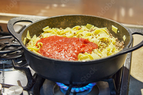 Spaghetti with ground beef and sauce, fried in pan for making spaghetti bolognese according to recipe from the Internet