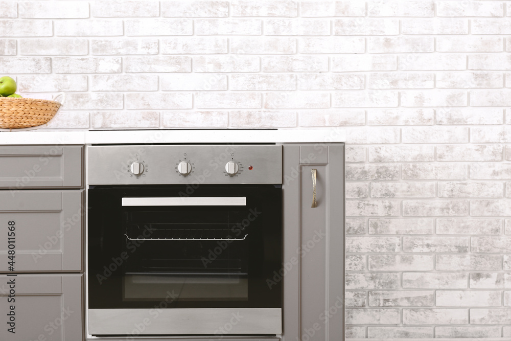 Fototapeta premium Modern kitchen counter with electric oven near brick wall