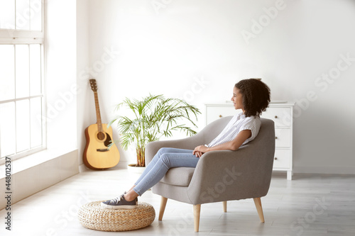 African-American girl relaxing in armchair at home