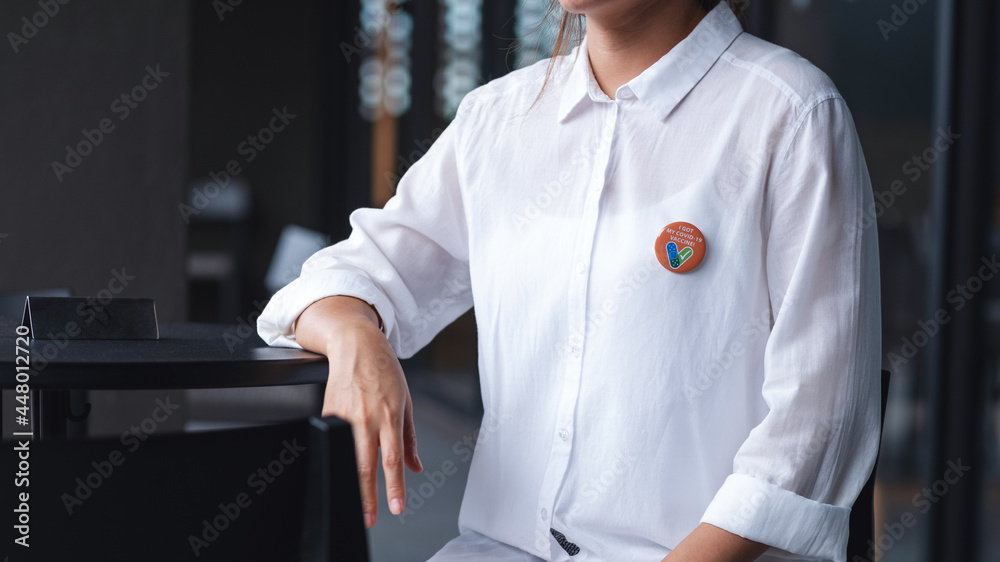 Closeup image of a woman with Covid-19 vaccinated sign brooch on shirt - obrazy, fototapety, plakaty 