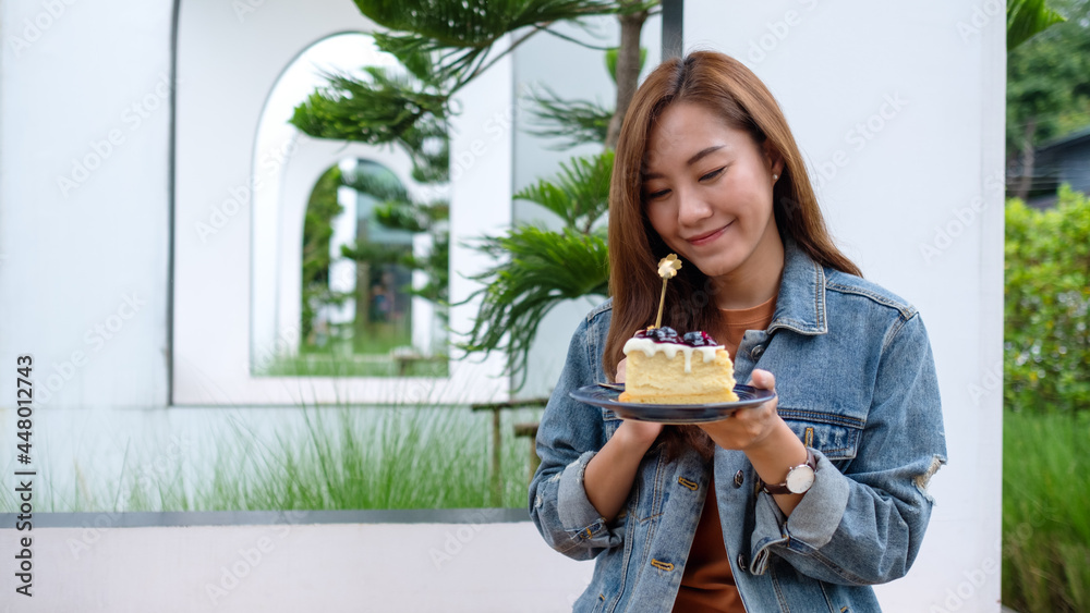 A beautiful young asian woman eating blueberry cheesecake A beautiful young asian woman eating blueberry cheesecake