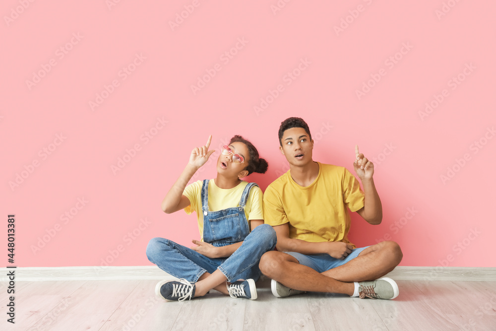 African-American brother and sister sitting near color wall African-American brother and sister sitting near color wall