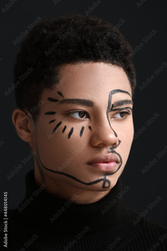Young African-American guy with paint on face against dark background Young African-American guy with paint on face against dark background