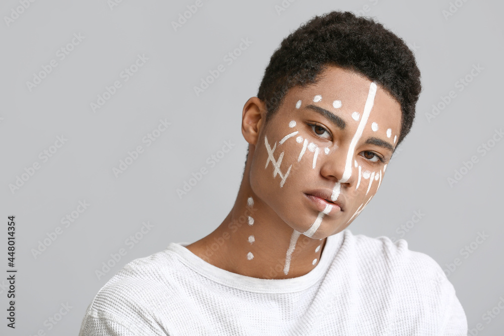 Young African-American guy with paint on face against light background Young African-American guy with paint on face against light background
