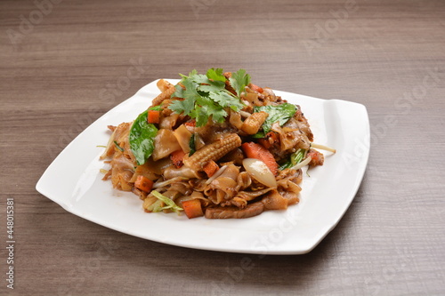 wok stir fried kway teow rice noodle mee goreng with vegetable in spicy soy chilli sauce on wood background asian halal vegan menu