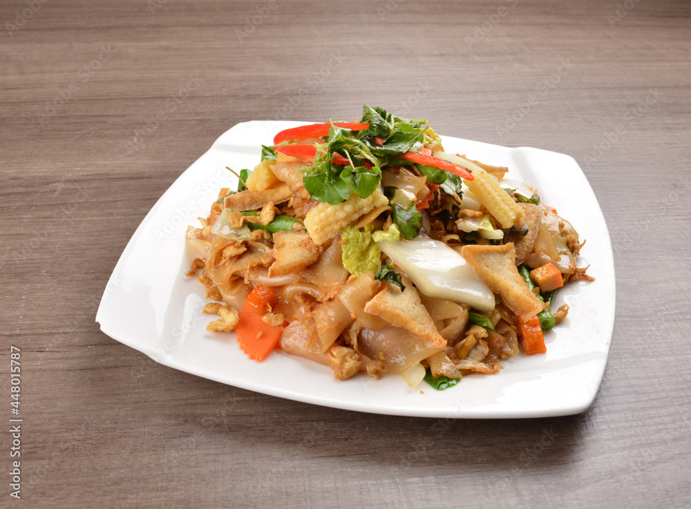 wok stir fried kway teow rice noodle mee goreng with vegetable in spicy soy chilli sauce on wood background asian halal vegan menu