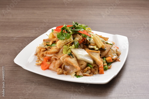 wok stir fried kway teow rice noodle mee goreng with vegetable in spicy soy chilli sauce on wood background asian halal vegan menu