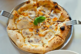 Pizza on a metal plate close up. Pizza with cheese, pear and pine nuts.