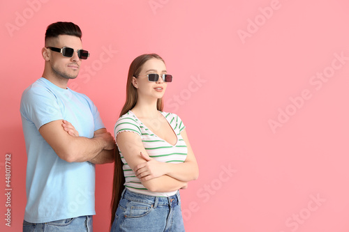 Young couple wearing stylish sunglasses on color background © Pixel-Shot