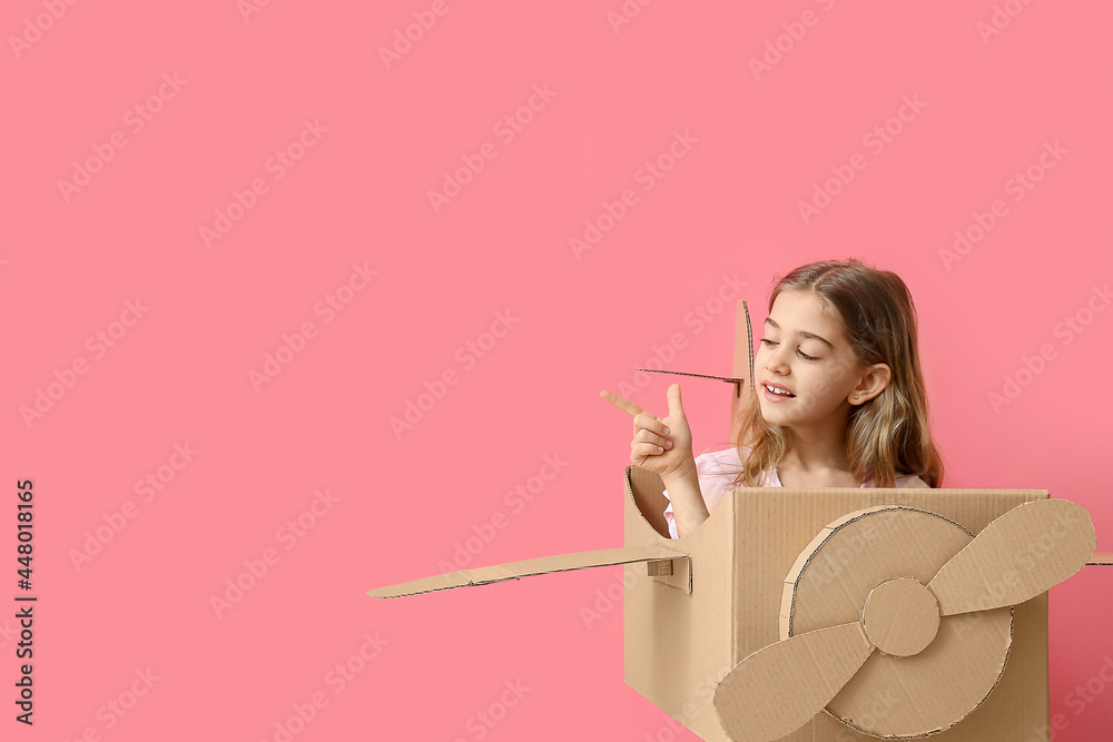 Little girl with cardboard airplane pointing at something on color background Little girl with cardboard airplane pointing at something on color background