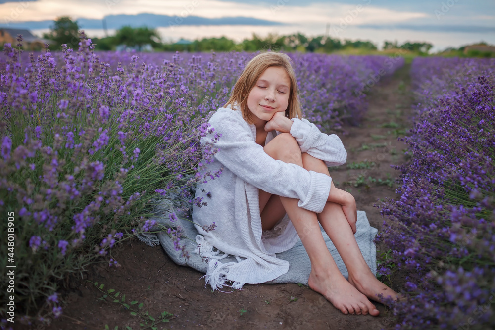 Teenage girl enjoys the scenery of lavender field. Dreamy teenager sitting among purple flowers. Calm landscape, escape to beauty of nature, summer lifestyle Teenage girl enjoys the scenery of lavender field. Dreamy teenager sitting among purple flowers. Calm landscape, escape to beauty of nature, summer lifestyle