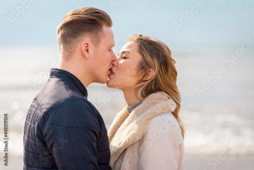 Young couple kissing outdoor.Stunning outdoors portrait of young stylish fashion couple posing in spring sea background.